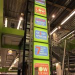 Kleurrijke reclameborden met teksten over bezorging, prijzen en gratis inbouwservice, bevestigd aan een metalen structuur.