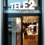 Een moderne winkel met grote raamopening, helder verlicht interieur en opvallend Tele2-logo boven de deur.