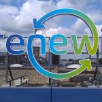 Felgekleurde reclame met het woord "renewi", omringd door een groene en blauwe cirkel, op een dak met een blauwe rand.